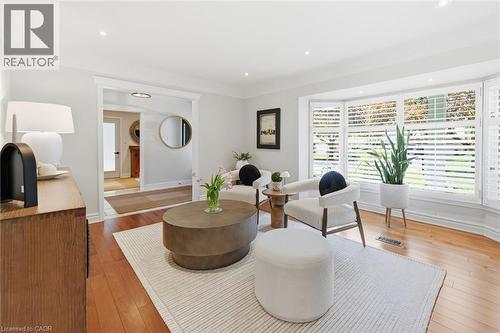 Living room featuring expansive bay windows with plantation shutters, recessed lighting, and hardwood flooring - 3500 Regal Road, Burlington, ON - Indoor