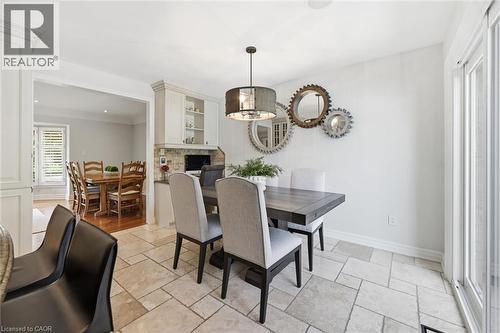 Stone-tiled flooring in an open-concept dining area featuring a built-in cabinetry unit with display shelving - 3500 Regal Road, Burlington, ON - Indoor Photo Showing Dining Room