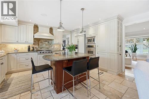 Gourmet kitchen with an expansive granite-topped island, integrated stainless steel appliances, and extensive cabinetry with crown molding - 3500 Regal Road, Burlington, ON - Indoor Photo Showing Kitchen With Upgraded Kitchen