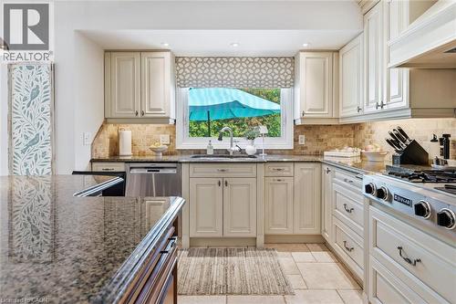 Kitchen featuring light-toned cabinetry, stone countertops, and a tiled backsplash - 3500 Regal Road, Burlington, ON - Indoor Photo Showing Kitchen With Upgraded Kitchen