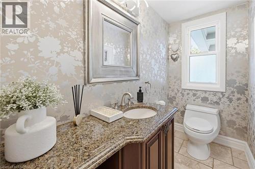 Powder room featuring botanical motif wallpaper, a single-pane window, and a vanity with a granite countertop and integrated sink - 3500 Regal Road, Burlington, ON - Indoor Photo Showing Bathroom