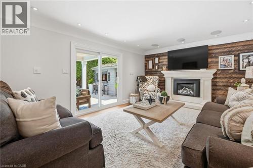 Living area featuring a stone mantel fireplace with a dark surround, a wood-finish accent wall, and recessed lighting - 3500 Regal Road, Burlington, ON - Indoor Photo Showing Living Room With Fireplace