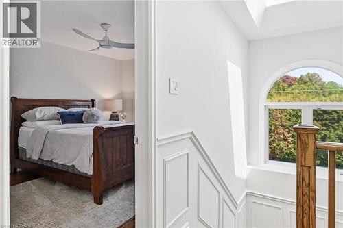 Stairwell with white wainscoting and a wood handrail, featuring an arched window and a skylight - 3500 Regal Road, Burlington, ON - Indoor Photo Showing Bedroom