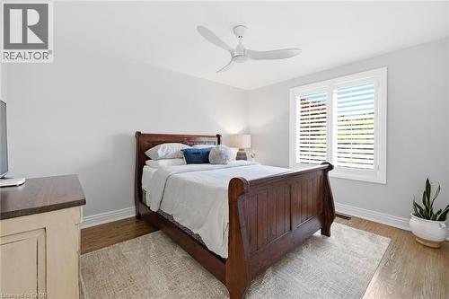 Light-filled room featuring wood-finish flooring, white baseboards, and a modern ceiling fan - 3500 Regal Road, Burlington, ON - Indoor Photo Showing Bedroom
