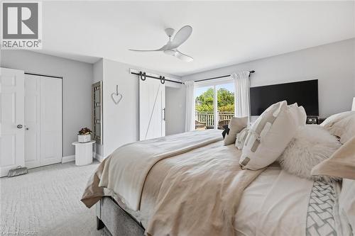 Room featuring a sliding barn door, a modern ceiling fan, and light-toned carpeting - 3500 Regal Road, Burlington, ON - Indoor Photo Showing Bedroom