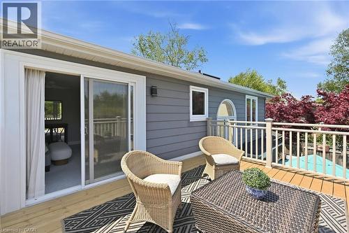 Wood-tone deck featuring white railings and gray siding - 3500 Regal Road, Burlington, ON - Outdoor With In Ground Pool With Backyard