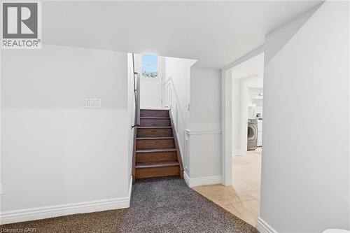 Staircase featuring wood-finish treads and a dark handrail, complemented by crisp white baseboards and trim - 3500 Regal Road, Burlington, ON - Indoor Photo Showing Bedroom