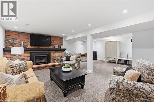 Finished interior space featuring a brick accent wall with an integrated fireplace and mantel, recessed lighting, and carpet flooring - 3500 Regal Road, Burlington, ON - Indoor Photo Showing Other Room
