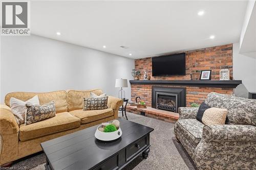 Living area featuring a brick accent wall with a fireplace and black mantel - 3500 Regal Road, Burlington, ON - Indoor Photo Showing Living Room With Fireplace