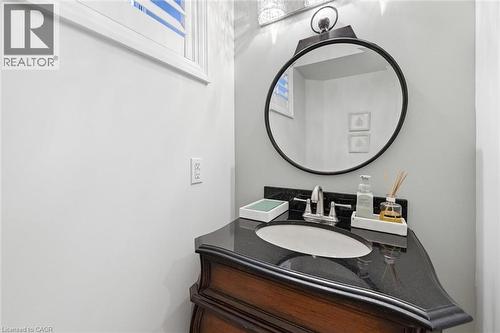Vanity with a dark countertop and undermount sink, illuminated by an overhead light fixture - 3500 Regal Road, Burlington, ON - Indoor Photo Showing Basement