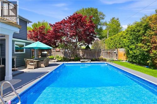 Rectangular in-ground swimming pool featuring a dark gray surround and a grass border - 3500 Regal Road, Burlington, ON - Outdoor With In Ground Pool With Deck Patio Veranda