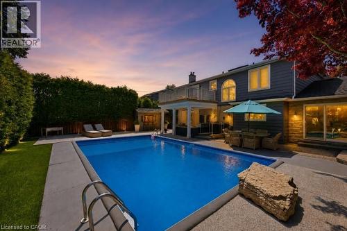 Rear exterior featuring an in-ground swimming pool, concrete patio, and mature privacy hedging - 3500 Regal Road, Burlington, ON - Outdoor With In Ground Pool With Deck Patio Veranda With Backyard With Exterior