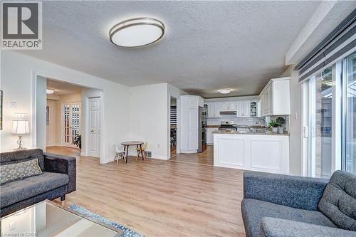 Bright living area featuring wood-finish flooring, recessed lighting, and a contemporary flush-mount ceiling fixture - 519 Yorkshire Drive, Waterloo, ON - Indoor Photo Showing Living Room