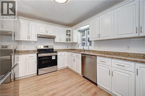 Kitchen featuring wood-finish flooring, white cabinetry, a stainless steel dishwasher, a stainless steel range, and stone countertops - 519 Yorkshire Drive, Waterloo, ON - Indoor Photo Showing Kitchen With Double Sink