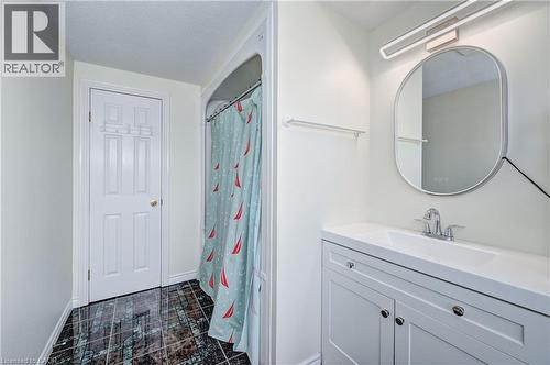 Bathroom featuring a contemporary vanity with an integrated sink, polished chrome faucet, and an oval-framed mirror with integrated lighting - 519 Yorkshire Drive, Waterloo, ON - Indoor Photo Showing Bathroom