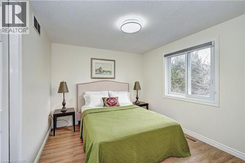Bedroom featuring wood-finish flooring, a contemporary ceiling light fixture, a large sliding window, and neutral wall paint - 519 Yorkshire Drive, Waterloo, ON - Indoor Photo Showing Bedroom