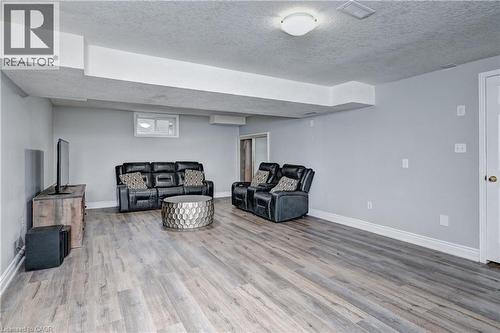 Spacious recreation room featuring light gray walls, white baseboards, and wood-finish flooring - 519 Yorkshire Drive, Waterloo, ON - Indoor