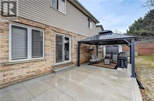 Poured concrete patio featuring a permanent metal gazebo, brick exterior, vinyl siding, and a sliding glass door - 519 Yorkshire Drive, Waterloo, ON - Outdoor With Deck Patio Veranda