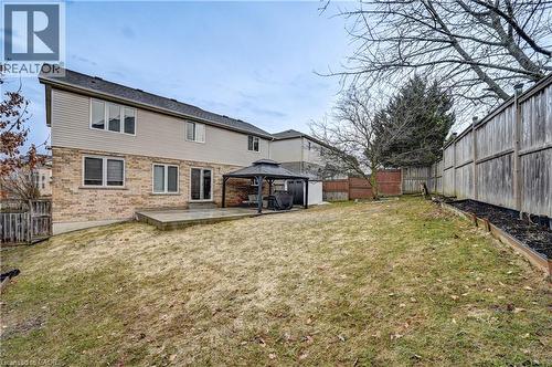 Expansive backyard featuring a concrete patio, brick and siding exterior, multiple windows, and a privacy fence - 519 Yorkshire Drive, Waterloo, ON - Outdoor