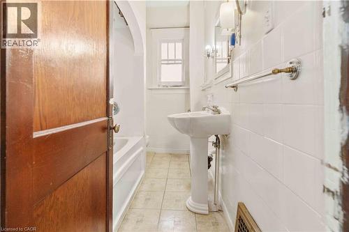 Bathroom featuring a pedestal sink, white subway tile wall surround, and a window with privacy panes - 151 Louisa Street, Kitchener, ON - Indoor Photo Showing Bathroom