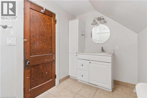 Bathroom featuring a single vanity with white cabinetry, a round mirror, and a wall-mounted light fixture - 151 Louisa Street, Kitchener, ON - Indoor Photo Showing Bathroom