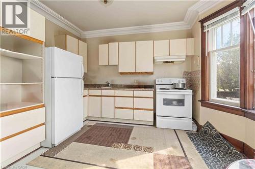 Kitchen featuring white cabinetry with wood-tone accents, a freestanding white refrigerator, and a white electric range with overhead ventilation - 151 Louisa Street, Kitchener, ON - Indoor Photo Showing Kitchen