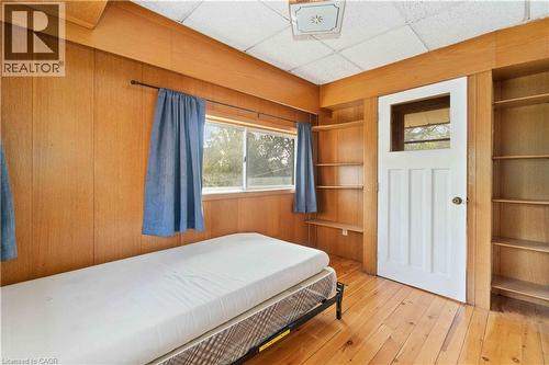 Room featuring wood-finish wall paneling, wood-finish flooring, a white paneled door with glass insert, and built-in shelving - 151 Louisa Street, Kitchener, ON - Indoor Photo Showing Bedroom