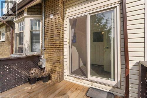 Exterior decking featuring a sliding glass door entry, brick siding, and a bay window with white trim - 151 Louisa Street, Kitchener, ON - Outdoor