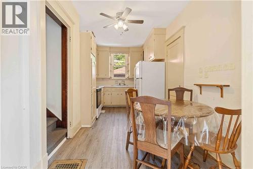 Compact kitchen featuring wood-finish flooring, cream-colored cabinetry, a white refrigerator, and a ceiling fan with integrated lighting - 151 Louisa Street, Kitchener, ON - Indoor Photo Showing Dining Room