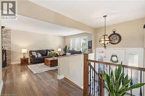 Open-concept living area with wood-finish flooring, a stone-accented wall, and a decorative ceiling light fixture - 2207 Jester Court, Burlington, ON - Indoor Photo Showing Other Room