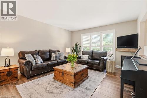 Living area with wood-finish flooring, light-toned walls, and a window featuring white plantation shutters - 2207 Jester Court, Burlington, ON - Indoor Photo Showing Living Room