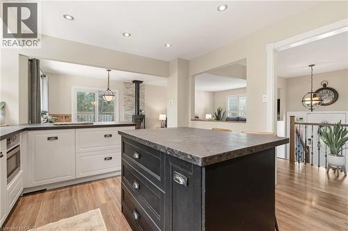 Kitchen featuring a dark-toned island with storage drawers, light-toned perimeter cabinetry with dark countertops, wood-finish flooring, and recessed ceiling lighting - 2207 Jester Court, Burlington, ON - Indoor Photo Showing Kitchen