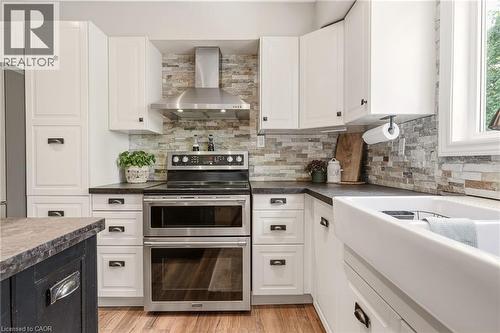Modern kitchen featuring white cabinetry, a large farmhouse sink, a stainless steel double oven range, and a stacked stone backsplash - 2207 Jester Court, Burlington, ON - Indoor Photo Showing Kitchen