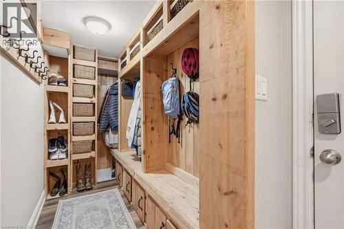 Mudroom featuring extensive built-in wooden cabinetry, integrated bench seating, multiple storage cubbies, wall-mounted coat hooks, and wood-finish flooring - 2207 Jester Court, Burlington, ON - Indoor