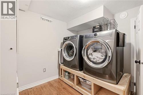Dedicated laundry area featuring wood-finish flooring, light neutral wall paint, and a built-in wooden platform for appliances - 2207 Jester Court, Burlington, ON - Indoor Photo Showing Laundry Room