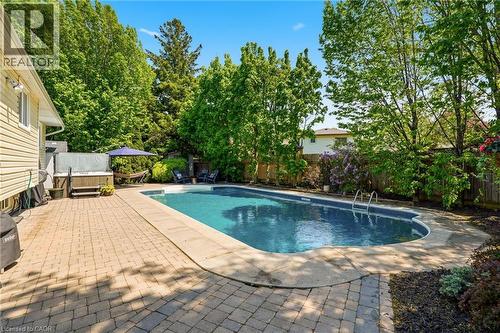 Outdoor swimming pool with integrated steps, surrounded by a concrete coping and a spacious paver patio - 2207 Jester Court, Burlington, ON - Outdoor With In Ground Pool With Backyard