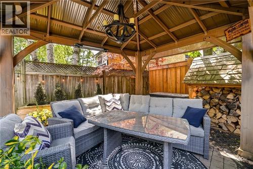 Wood pergola with a corrugated metal roof, featuring a built-in outdoor heater and a central chandelier - 2207 Jester Court, Burlington, ON - Outdoor With Deck Patio Veranda