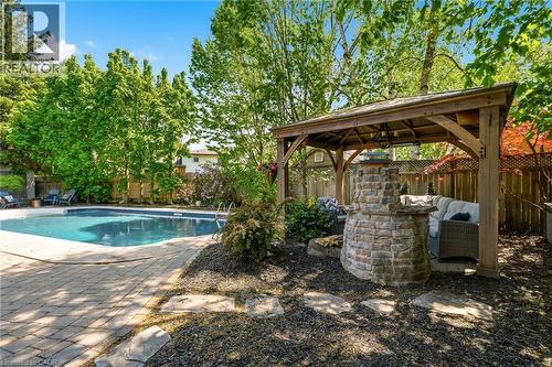 Outdoor living area featuring a custom wooden gazebo with a stone fireplace - 2207 Jester Court, Burlington, ON - Outdoor With In Ground Pool With Backyard