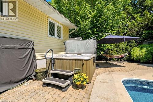 Outdoor spa with steps and safety railing, set on a paver patio alongside a swimming pool - 2207 Jester Court, Burlington, ON - Outdoor With In Ground Pool