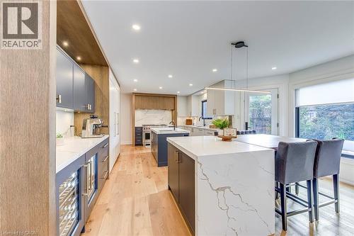 Open-concept kitchen featuring wood-finish flooring, recessed lighting, and a large central island with a waterfall countertop - 54 Deerview Avenue, Ancaster, ON - Indoor Photo Showing Kitchen With Upgraded Kitchen