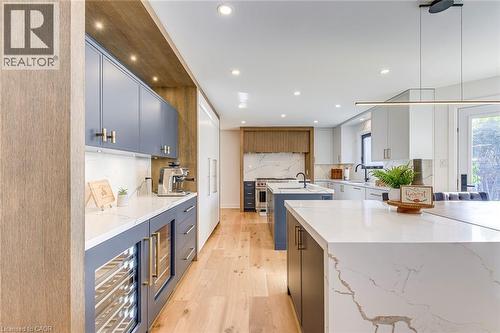 Contemporary kitchen featuring light wood-finish flooring, recessed lighting, and a large central island with a waterfall countertop - 54 Deerview Avenue, Ancaster, ON - Indoor Photo Showing Kitchen With Upgraded Kitchen
