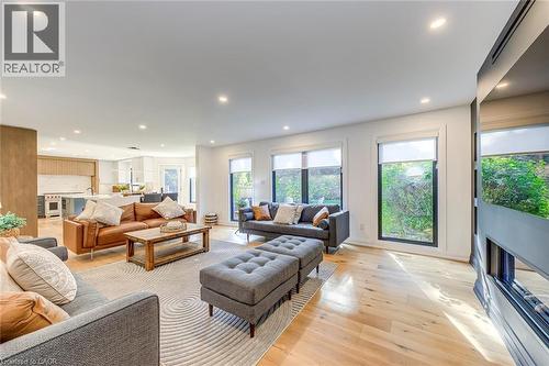 Open-concept living area featuring light wood-finish flooring, recessed lighting, and large windows with roller shades - 54 Deerview Avenue, Ancaster, ON - Indoor Photo Showing Living Room With Fireplace