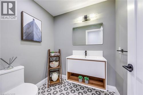 Modern bathroom featuring patterned floor tiles, a floating vanity with integrated sink, and a sleek rectangular mirror - 54 Deerview Avenue, Ancaster, ON - Indoor Photo Showing Bathroom