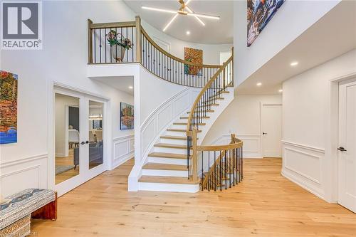Grand curved staircase featuring light wood treads, dark iron balusters, and a light wood handrail - 54 Deerview Avenue, Ancaster, ON - Indoor Photo Showing Other Room