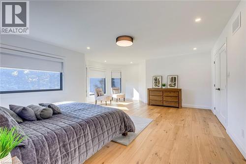 Spacious room featuring wood-finish flooring, recessed lighting, and a contemporary ceiling fixture - 54 Deerview Avenue, Ancaster, ON - Indoor Photo Showing Bedroom