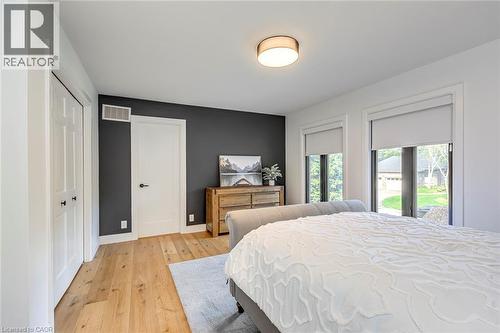 Light wood-finish flooring complements the contrasting accent wall - 54 Deerview Avenue, Ancaster, ON - Indoor Photo Showing Bedroom