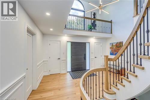 Two-story foyer featuring a curved staircase with natural wood handrails and wrought iron balusters, recessed lighting, and light wood-finish flooring - 54 Deerview Avenue, Ancaster, ON - Indoor Photo Showing Other Room