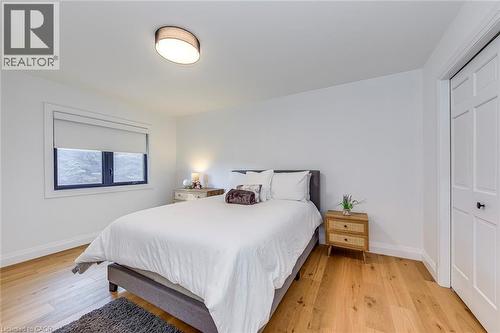Bedroom featuring wide-plank wood-finish flooring, white walls, and a window with a roller shade - 54 Deerview Avenue, Ancaster, ON - Indoor Photo Showing Bedroom