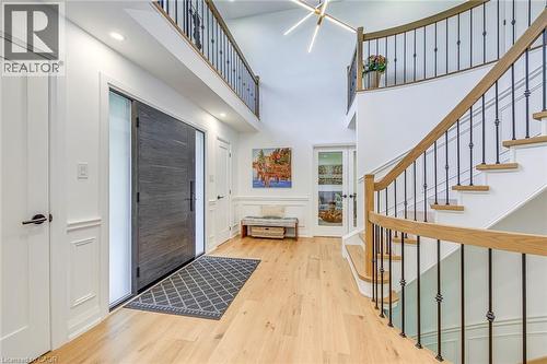 Two-story entryway featuring a contemporary dark wood-finish door with sidelight, light wood-finish flooring, a grand staircase with wood-finish handrails and black iron balusters, recessed lighting, - 54 Deerview Avenue, Ancaster, ON - Indoor Photo Showing Other Room