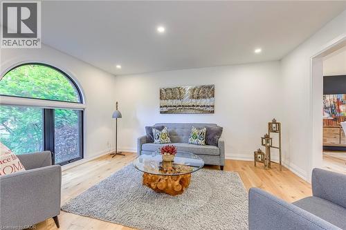 Bright living space featuring a large arched window, light wood-finish flooring, recessed lighting, and a wide entryway - 54 Deerview Avenue, Ancaster, ON - Indoor Photo Showing Living Room